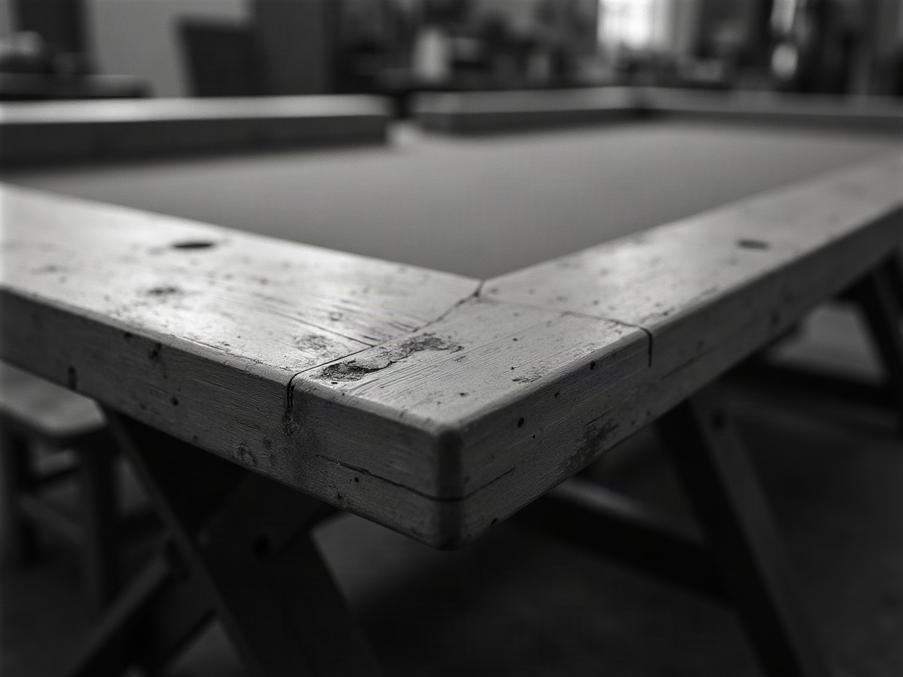Detalle de una mesa de juego plegable a medio armar, con bisagra metálica visible